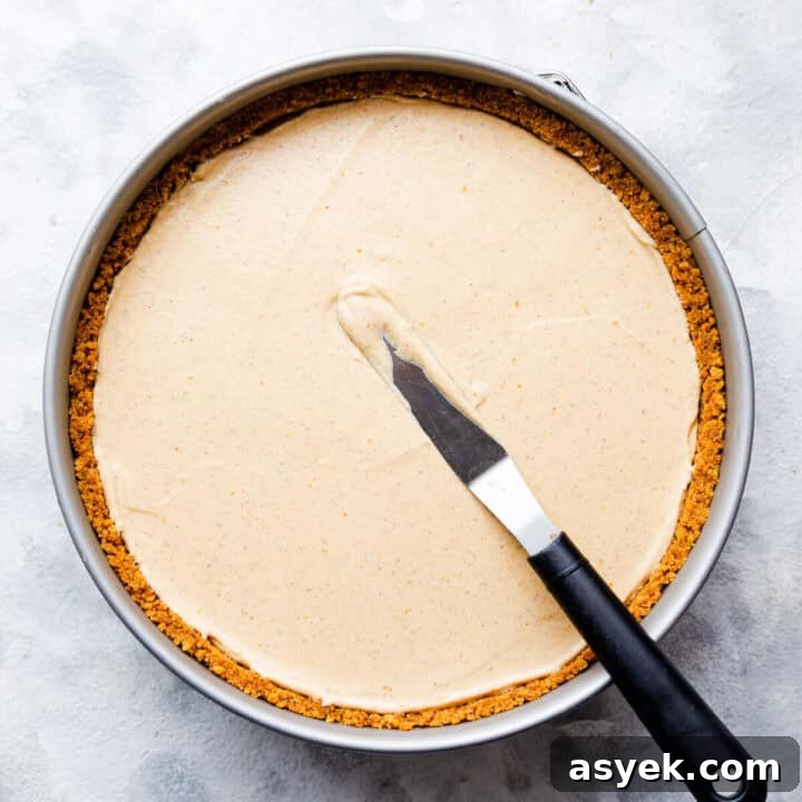 Creamy No-Bake Pumpkin Cheesecake Recipe 10 top view of a round baking tin with pumpkin cheesecake inside and small offset spatula on tiop