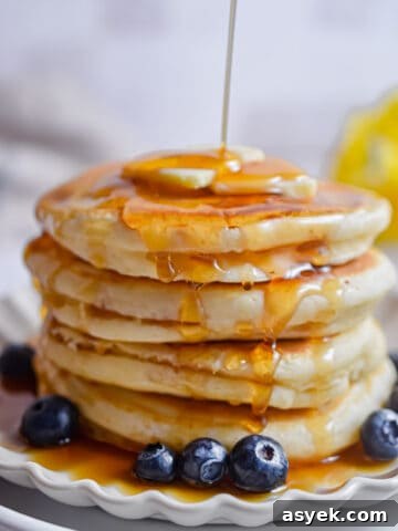 Maple syrup is being poured onto the pancakes.