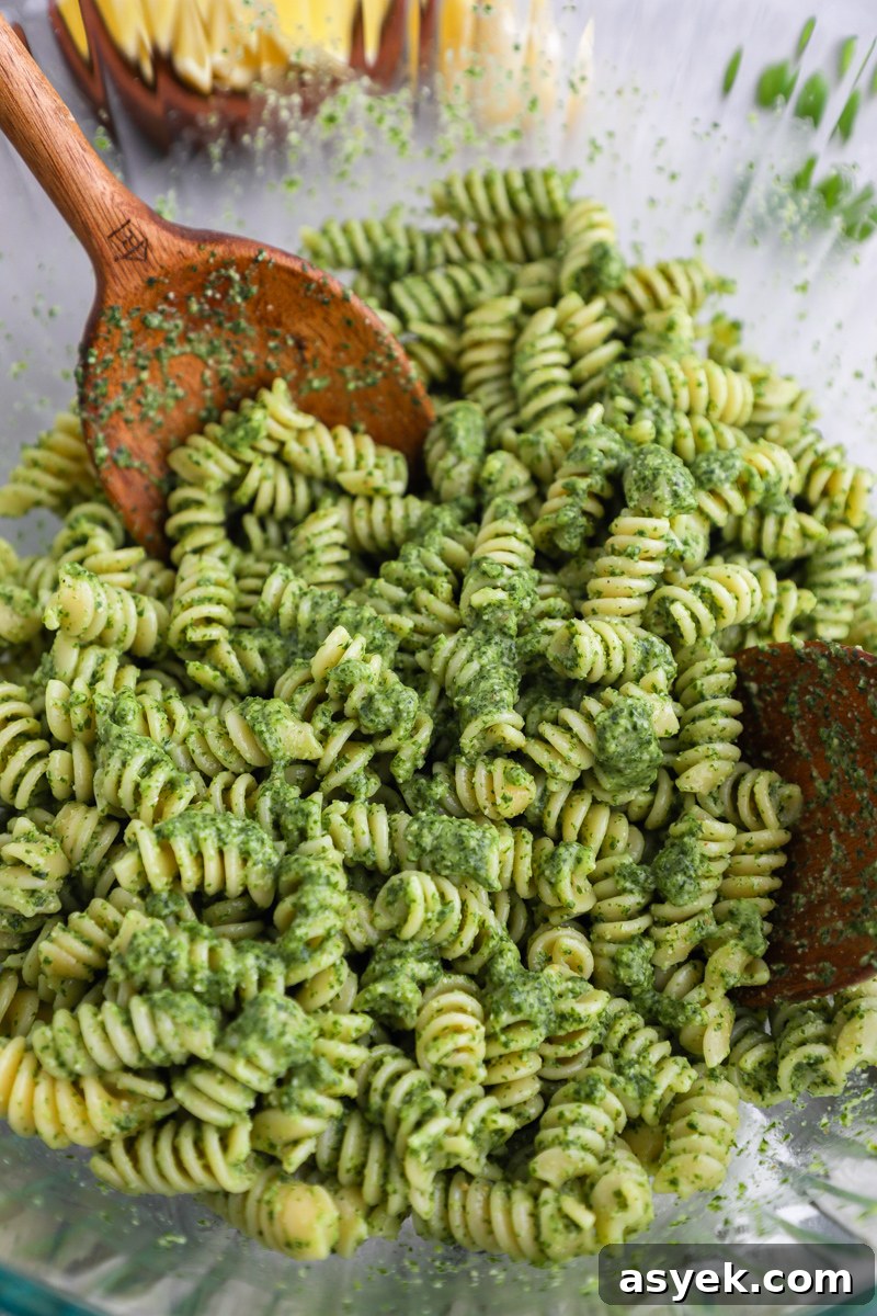 Kale Pesto Pasta with Homemade Pesto Sauce 5 A clear mixing bowl filled with cooked rotini pasta mixed with homemade kale pesto
