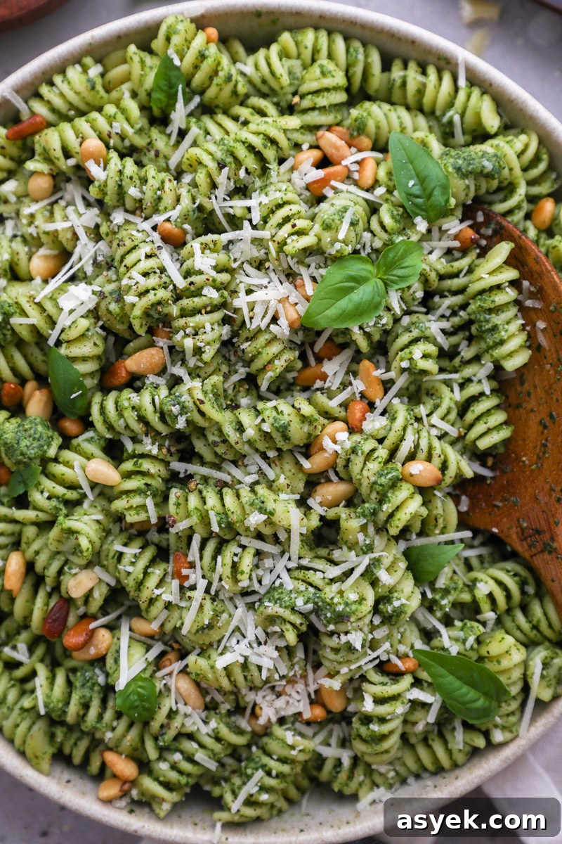 Kale Pesto Pasta with Homemade Pesto Sauce 7 A close up photo of a bowl filled with kale pesto pasta with a wooden serving spoon digging into it