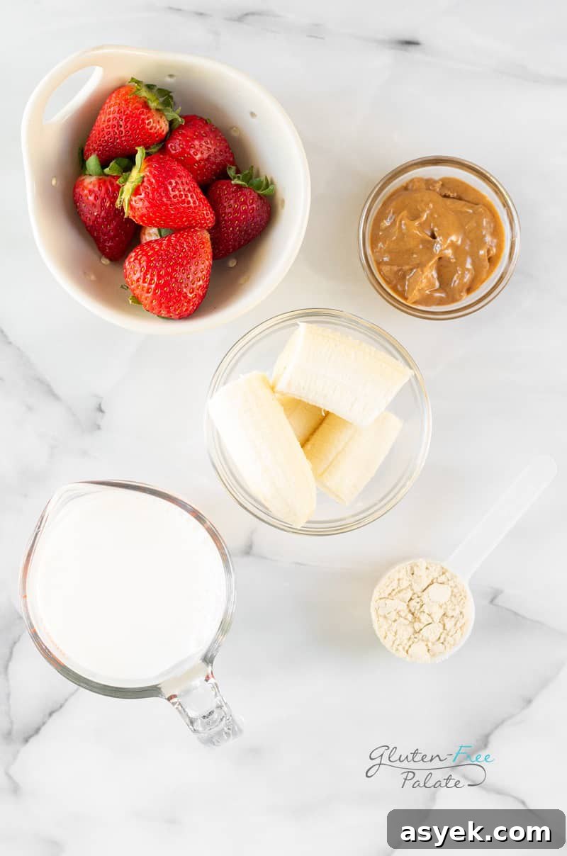 Creamy Strawberry Banana Peanut Butter Smoothie Recipe 4 Ingredients for strawberry banana peanut butter smoothie, all in separate bowls on a marble counter.