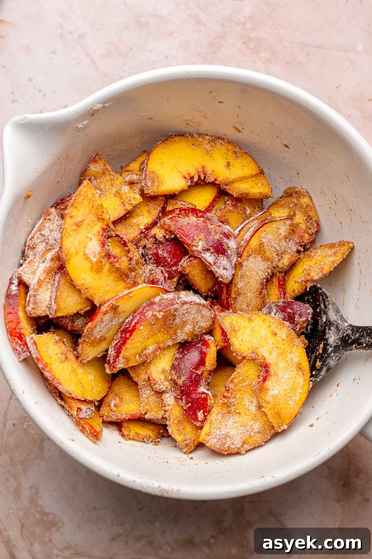 Brown Butter Peach Crumble Bars Recipe 8 Sliced peaches mixed with flour and spices in a bowl.