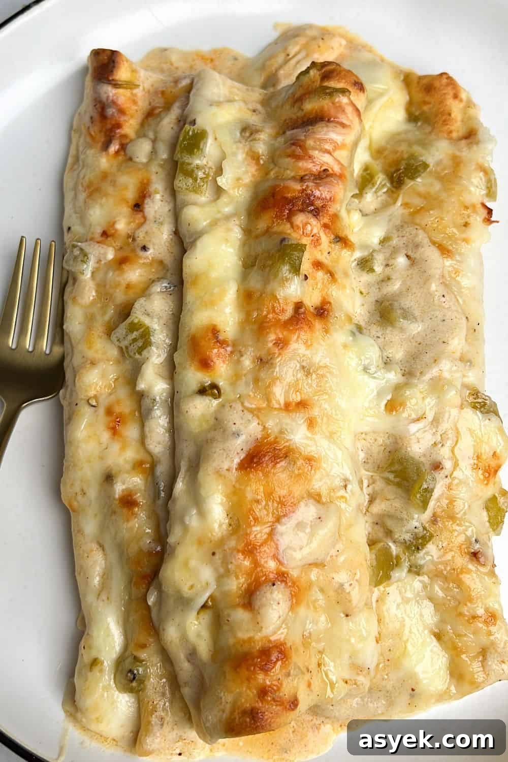 three white chicken enchiladas sitting on a plate