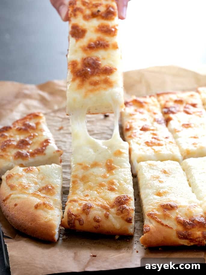 Crispy Gluten-Free Garlic Pizza Breadsticks Recipe 2 Pulling one garlic pizza breadstick with cheese trailing