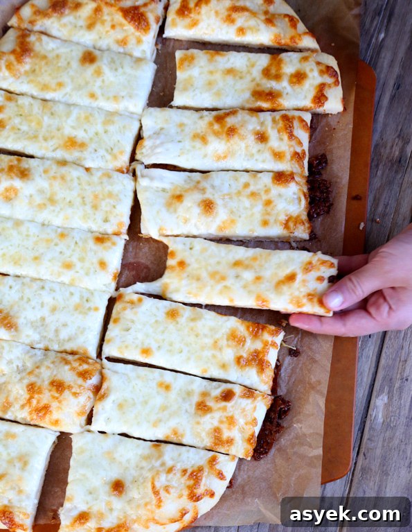 Crispy Gluten-Free Garlic Pizza Breadsticks Recipe 9 Garlic breadsticks pictured from above with a hand taking one