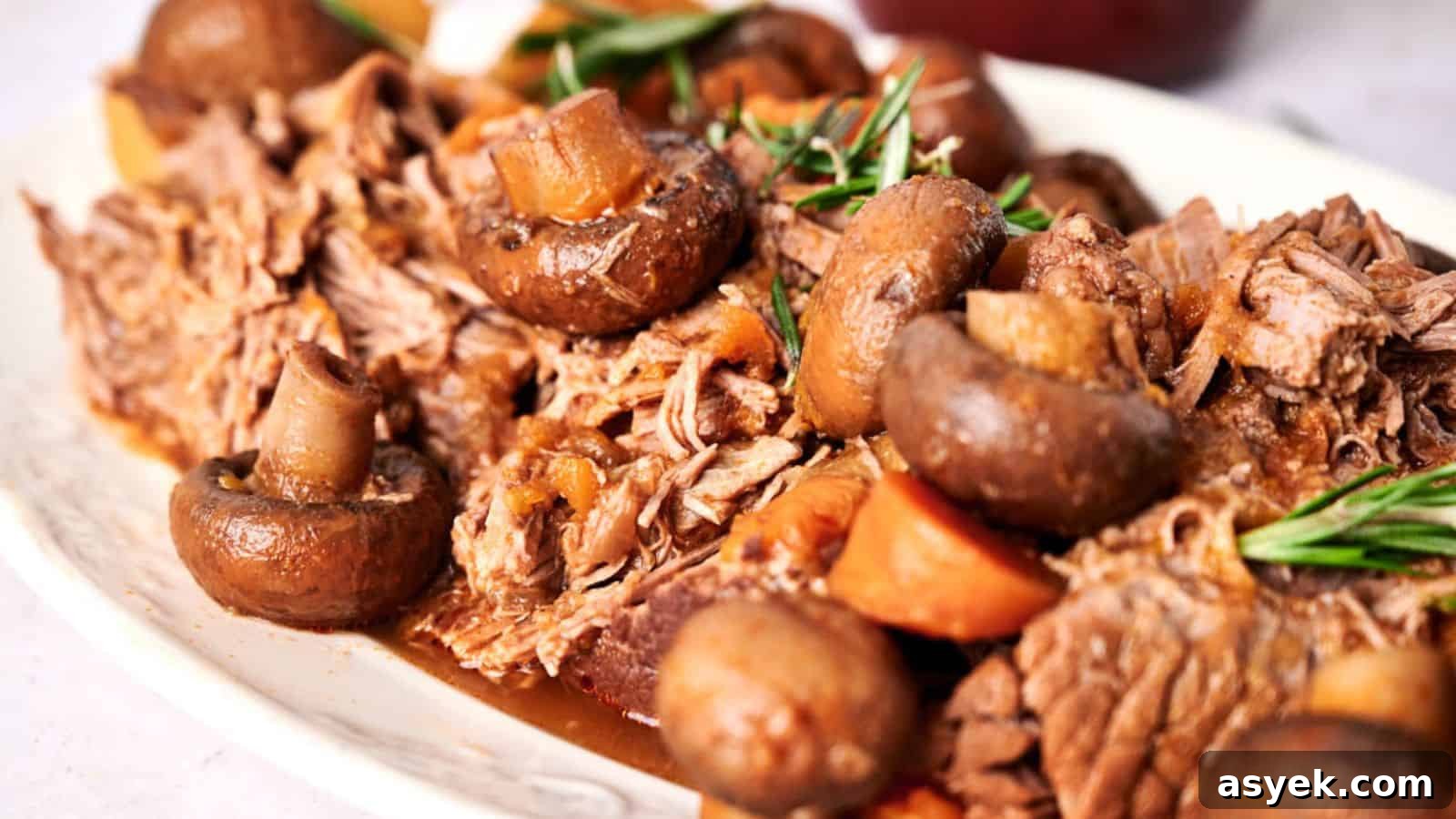 Slow cooker pot roast with mushrooms and carrots garnished with fresh rosemary.