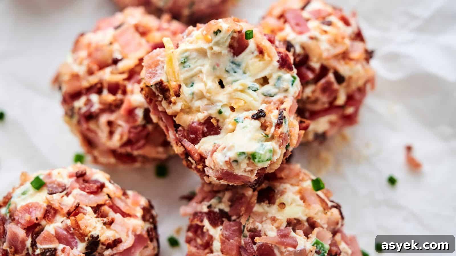 Close-up of several Bacon Jalapeno Popper Cheese Balls wrapped in bacon, stuffed with cheese, and seasoned with herbs and spices, placed on crumpled parchment paper.