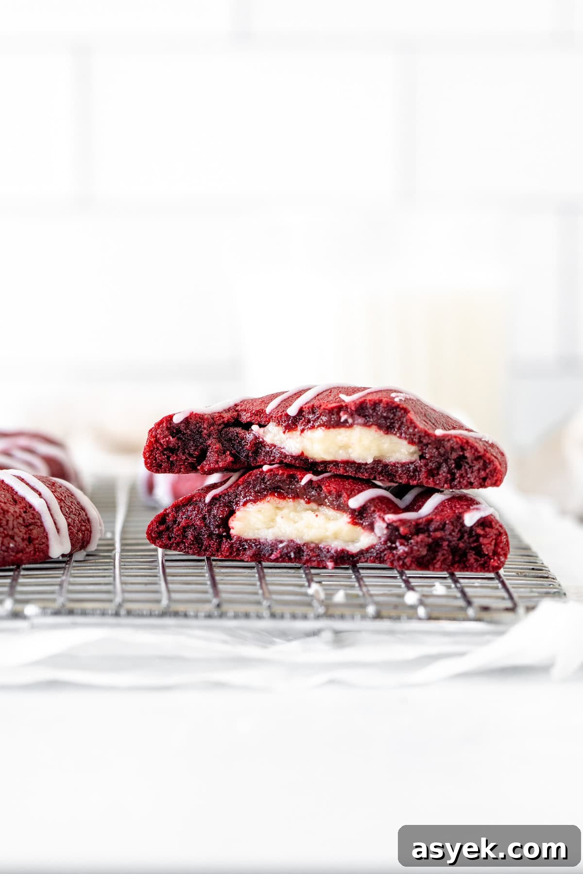 Red Velvet Cookies with Cream Cheese Filling 8 Red velvet cheesecake cookie broken in half on cooling rack