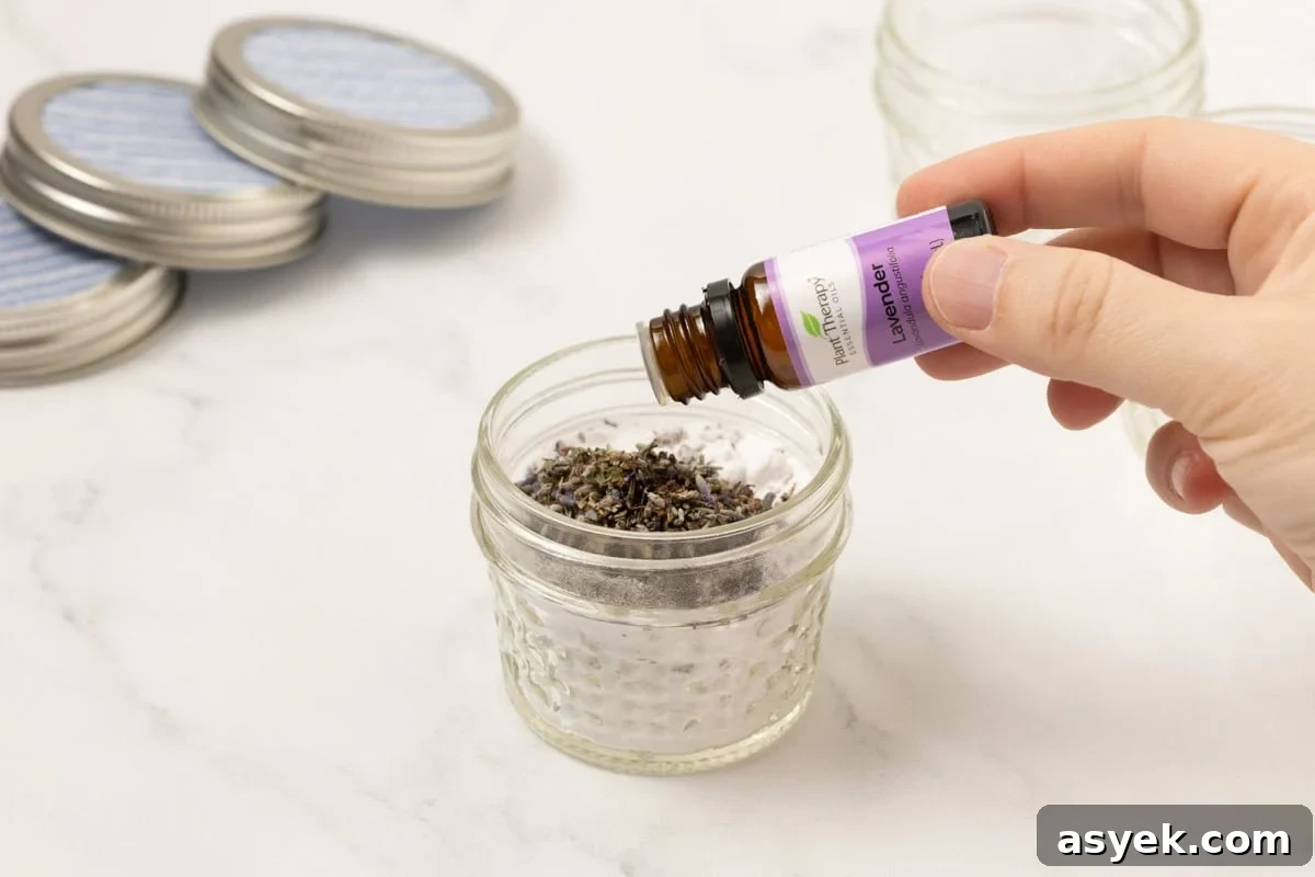 lavender essential oil being added to baking soda and lavender buds in a mason jar