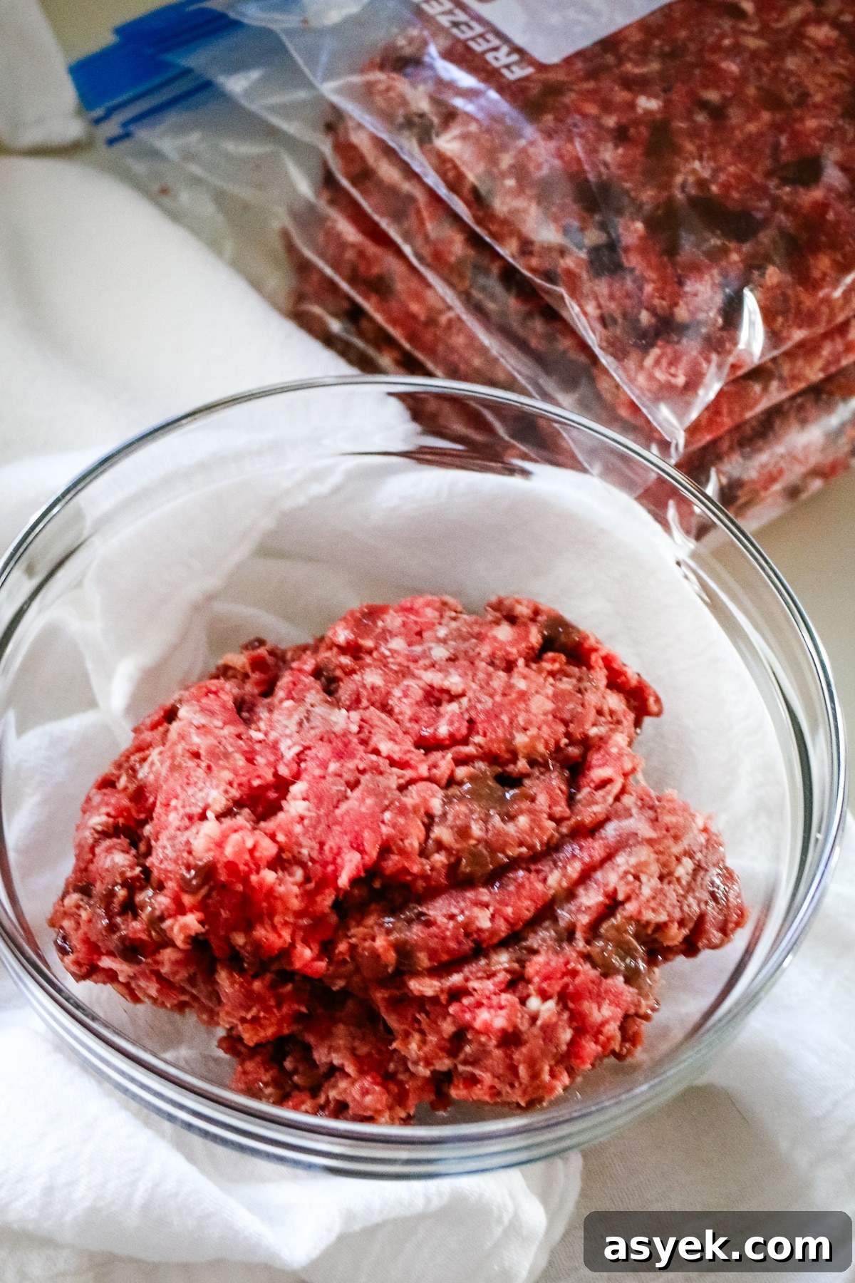 Ground beef with organ meat in a clear bowl and a freezer ziplock on the side.