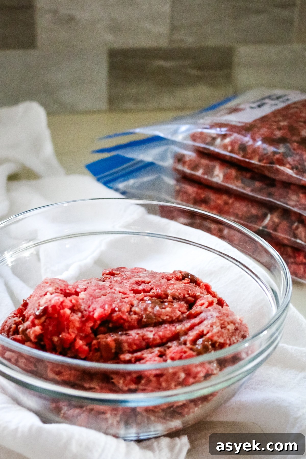 Ground beef with organ meat in a clear bowl and a freezer ziplock on the side.