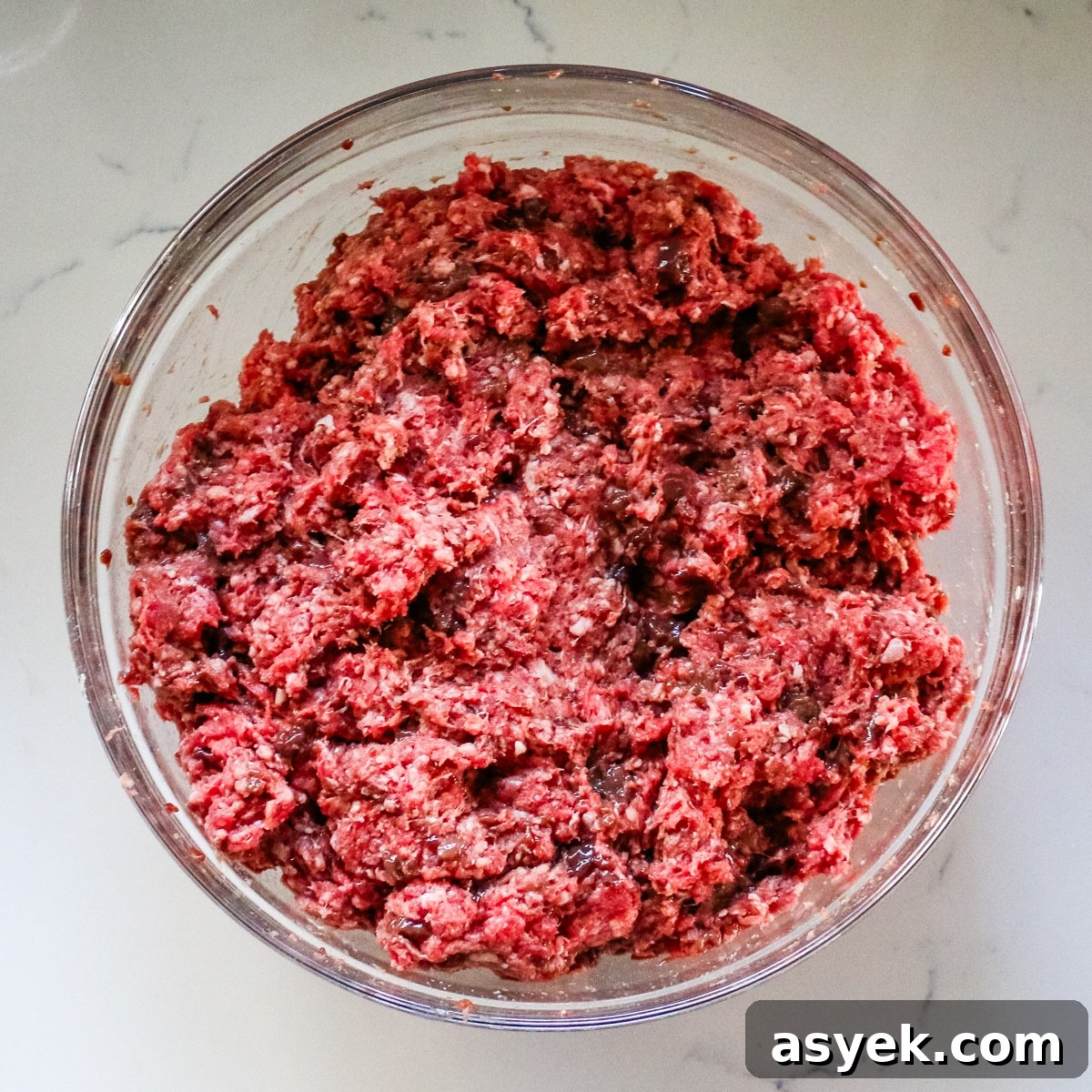 Ground beef mixed with organ meat in a clear bowl.