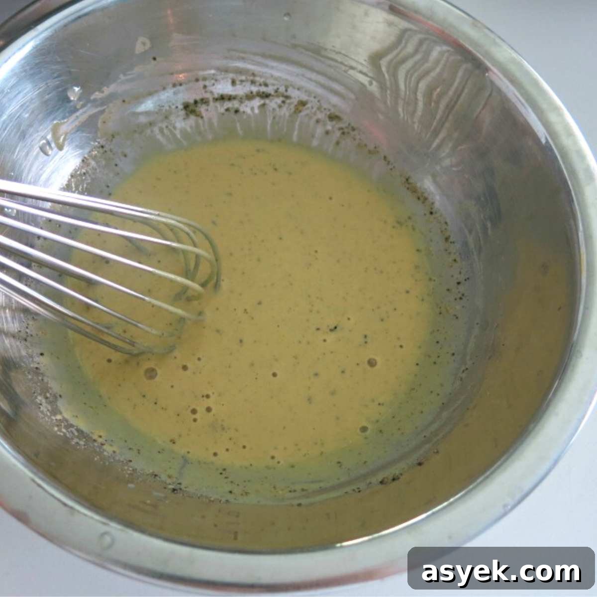 Crispy Parmesan Herb-Crusted Chicken Recipe 3 Dijon mustard, lemon sauce in a bowl with a whisk.
