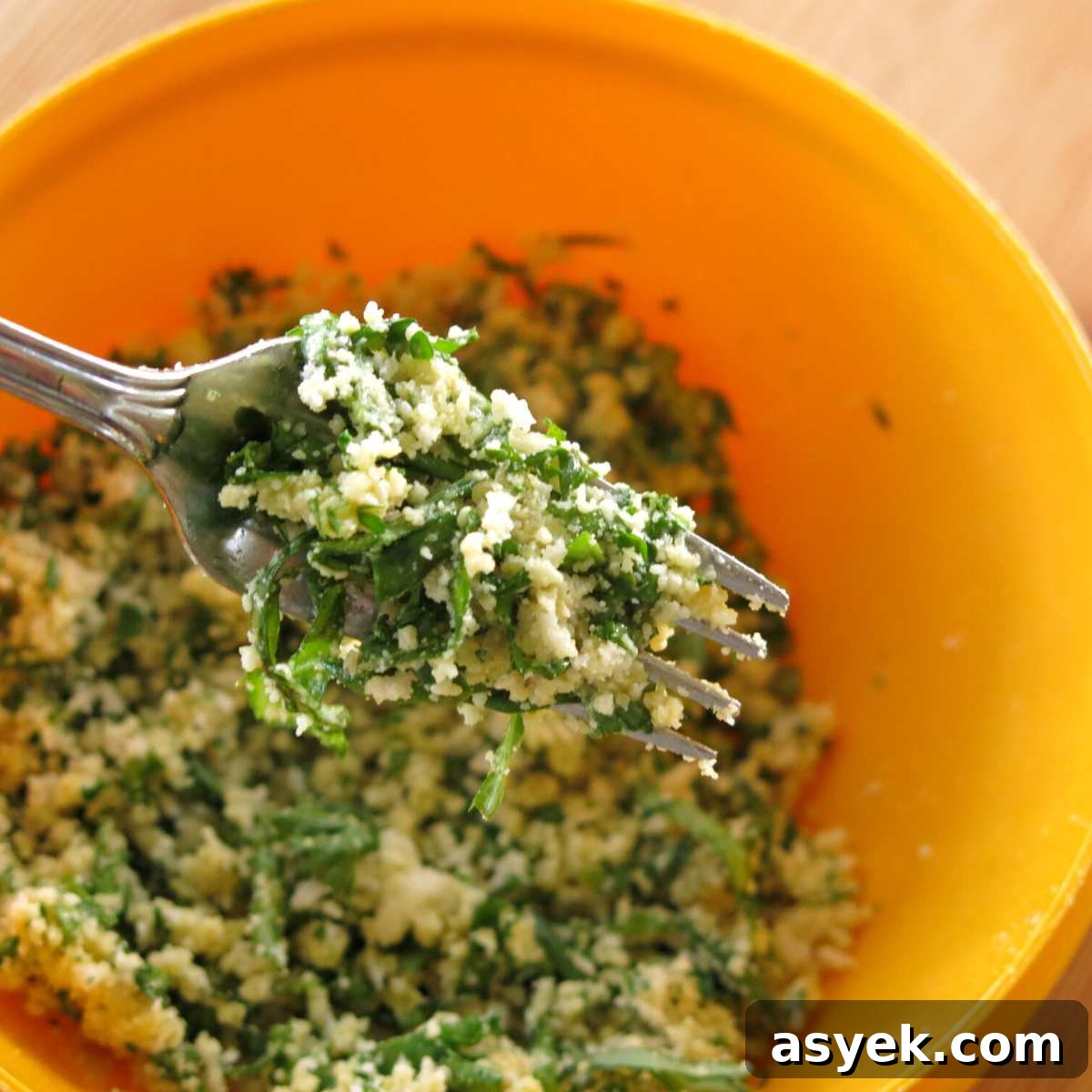 Crispy Parmesan Herb-Crusted Chicken Recipe 4 Fork holding fresh herb and Parmesan breading over a bowl with more.
