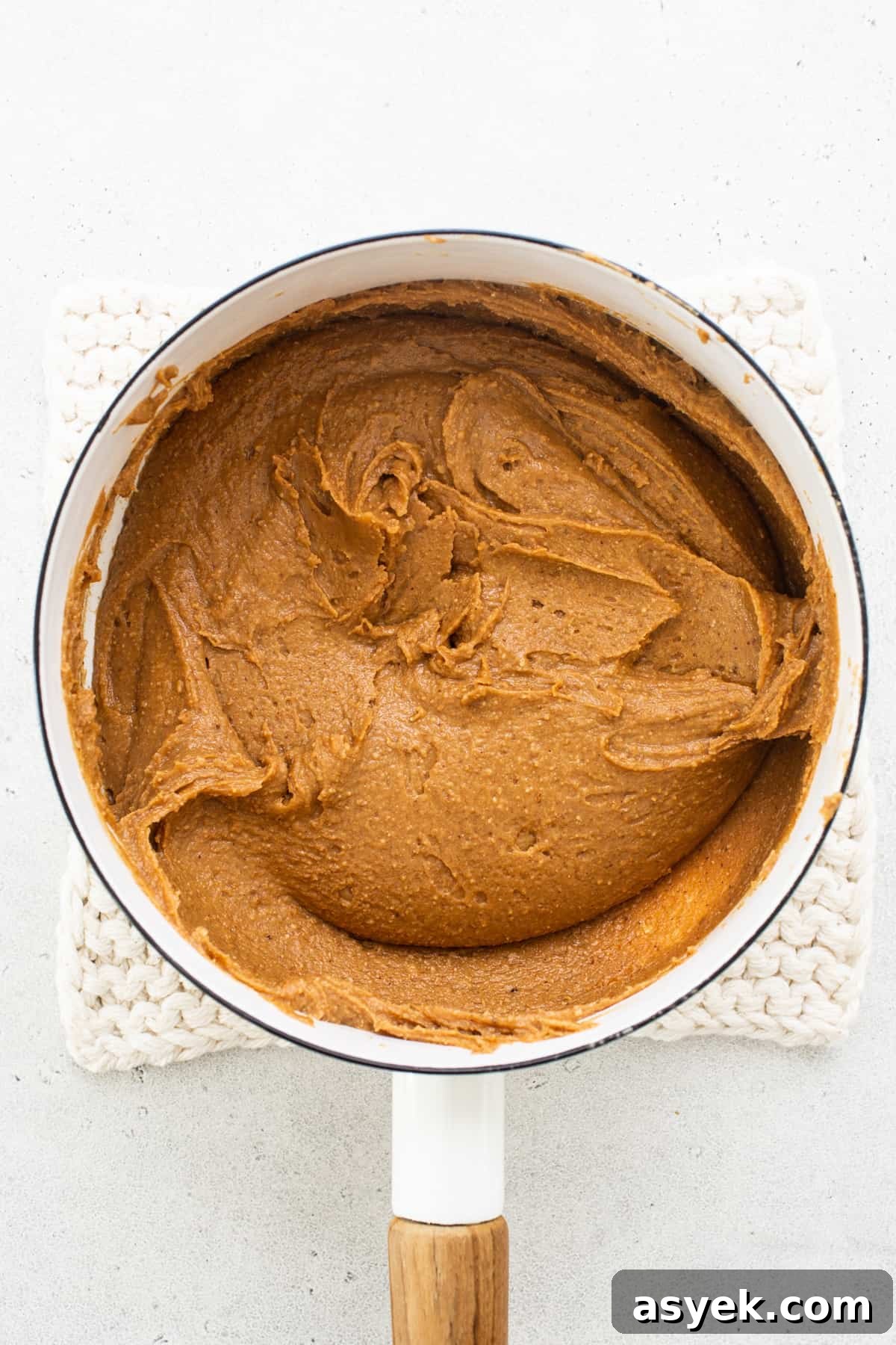 Pumpkin butter in a pan with a wooden spoon.