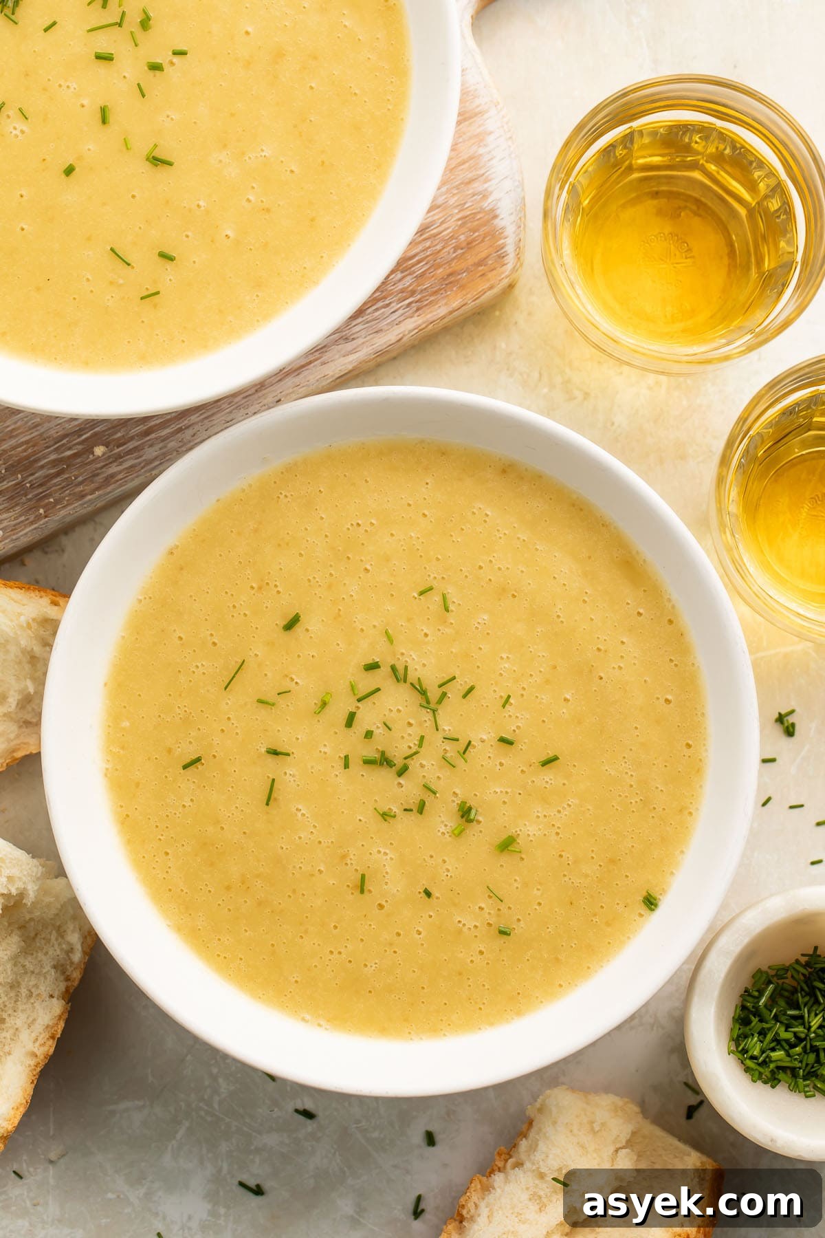 Instant Pot Creamy Potato Leek Soup 2 Bowls of yellow, creamy potato leek soup cooked in an Instant Pot on a table top with pieces of crusty bread surrounding.