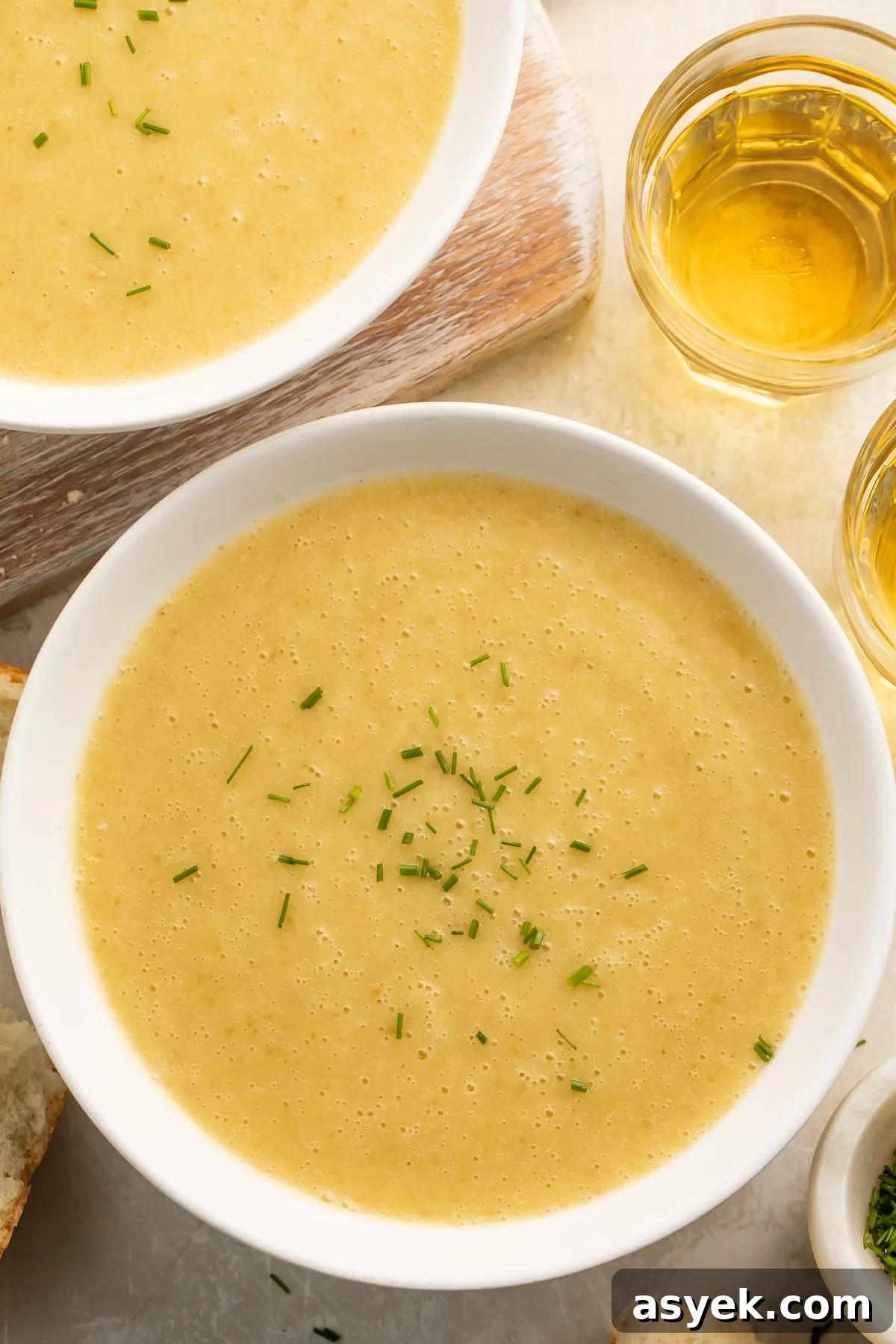 Instant Pot Creamy Potato Leek Soup 3 Bowls of yellow, creamy potato leek soup cooked in an Instant Pot on a table top with pieces of crusty bread surrounding.
