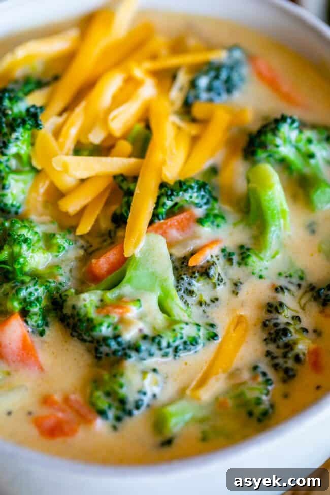 easy broccoli cheese soup in a white bowl, with cheddar cheese on top.