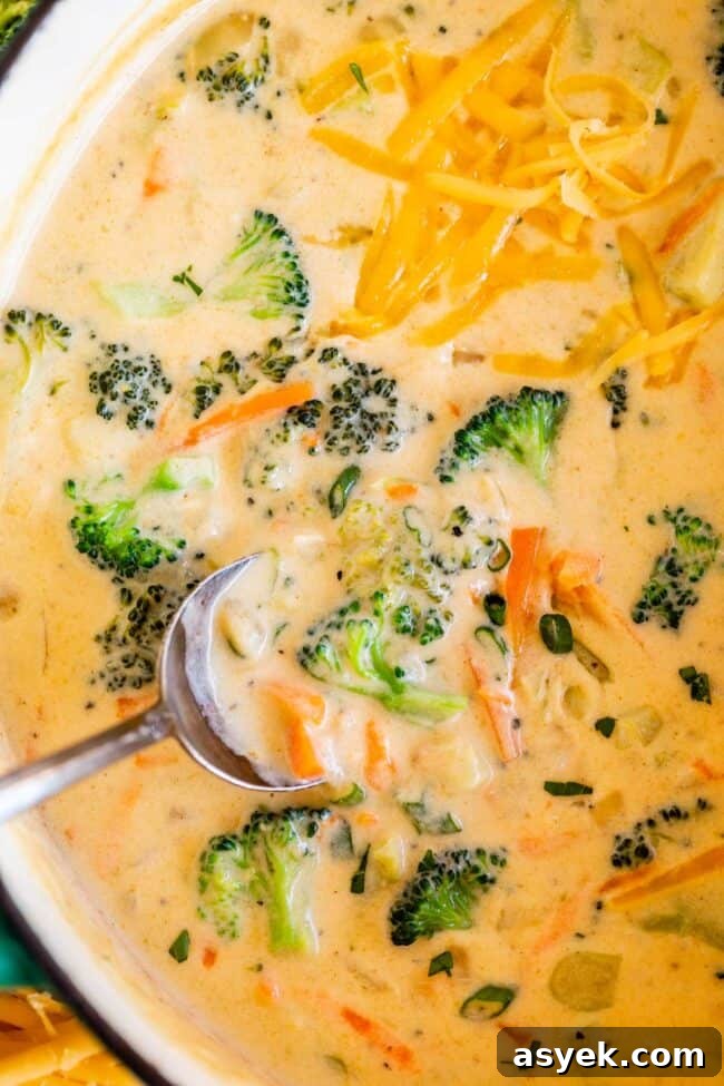 easy broccoli cheese soup in a pot with a silver spoon lifting a bite.