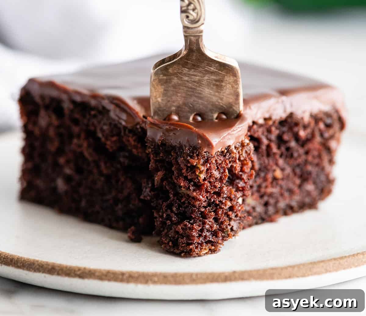 Moist Chocolate Zucchini Cake Recipe 10 front view of a fork taking a bite of chocolate zucchini cake