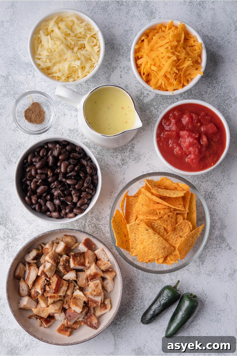 Mexican Chicken Casserole Recipe with Cheesy Tortilla Topping 5 An assortment of ingredients including bowls of diced chicken, black beans, tortilla chips, crushed tomatoes, cheese, soup, and spices.