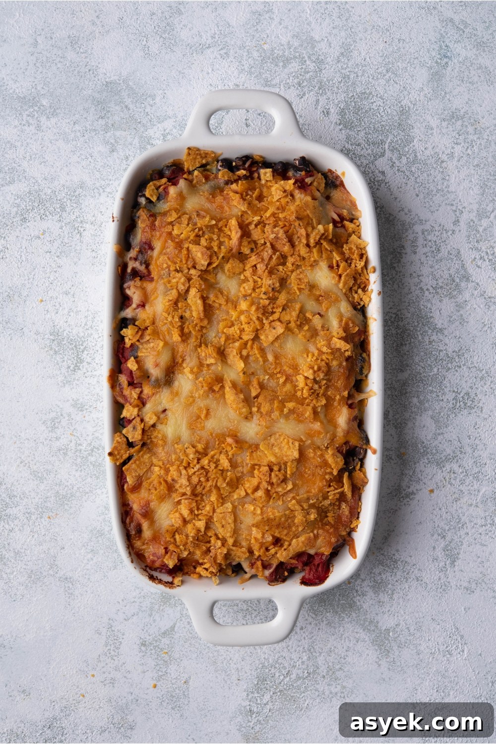 Mexican Chicken Casserole Recipe with Cheesy Tortilla Topping 7 White baking dish with baked Mexican chicken casserole.