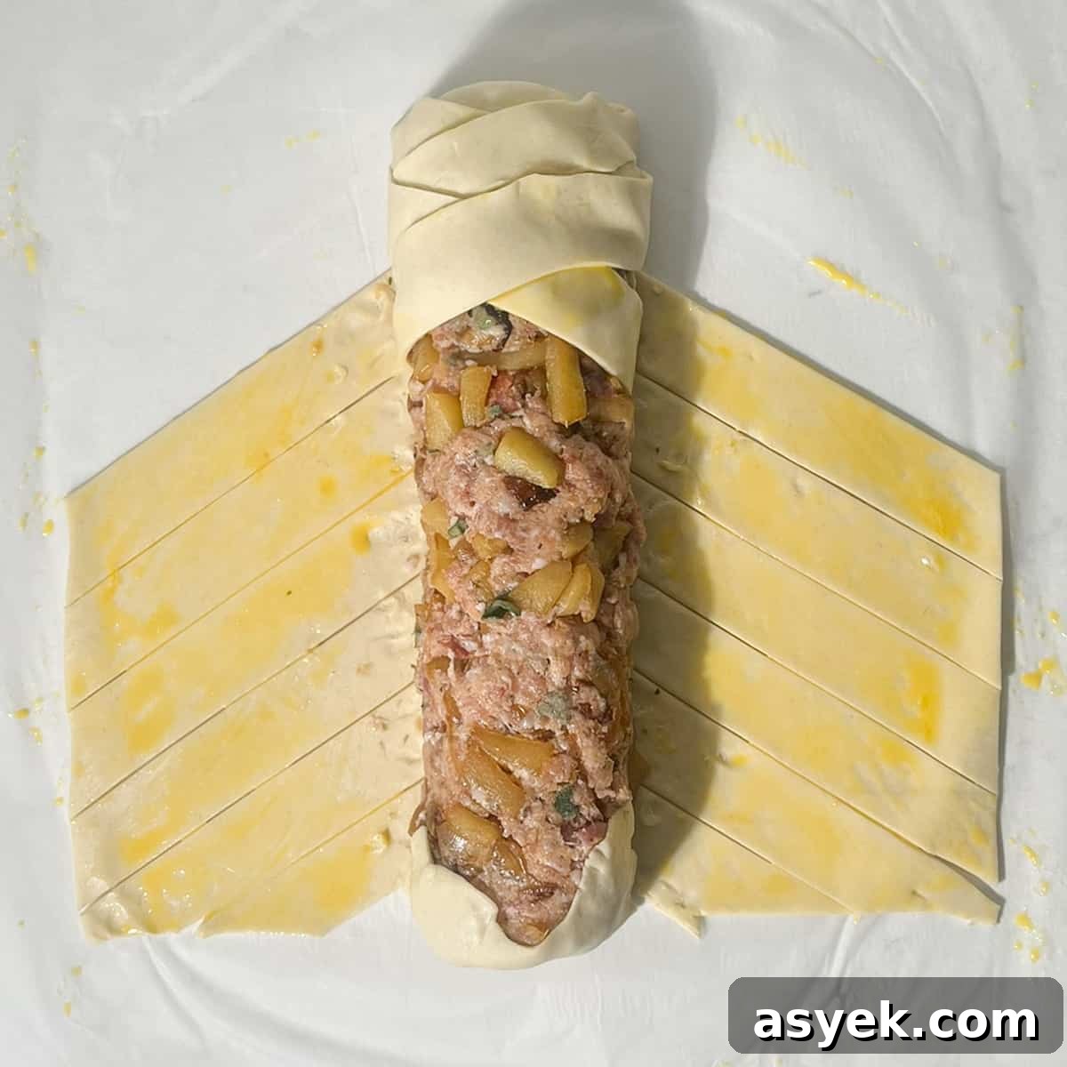 Plaiting the pastry across the sausage meat mixture.