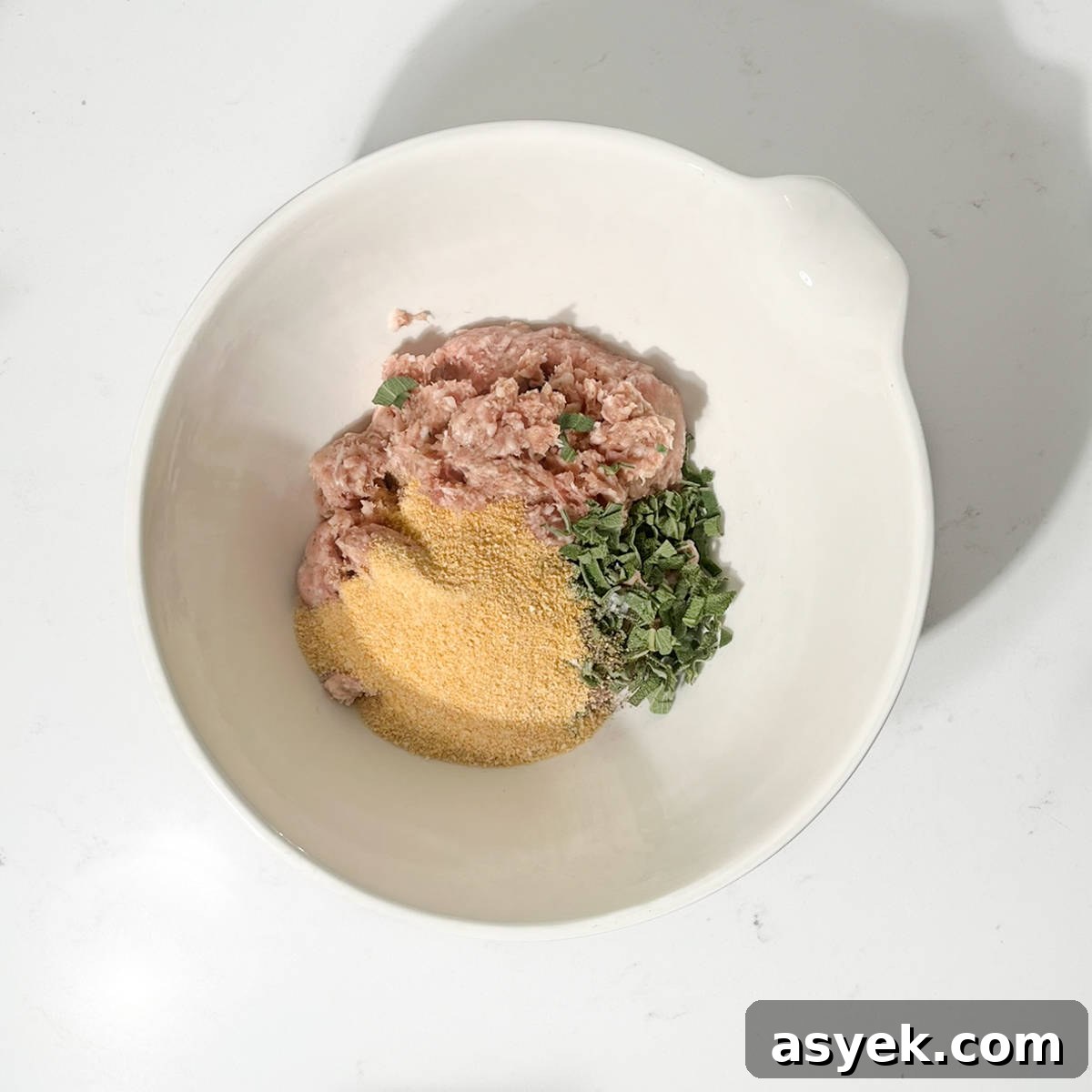 Adding the breadcrumbs, sage and sausage meat to a large bowl.