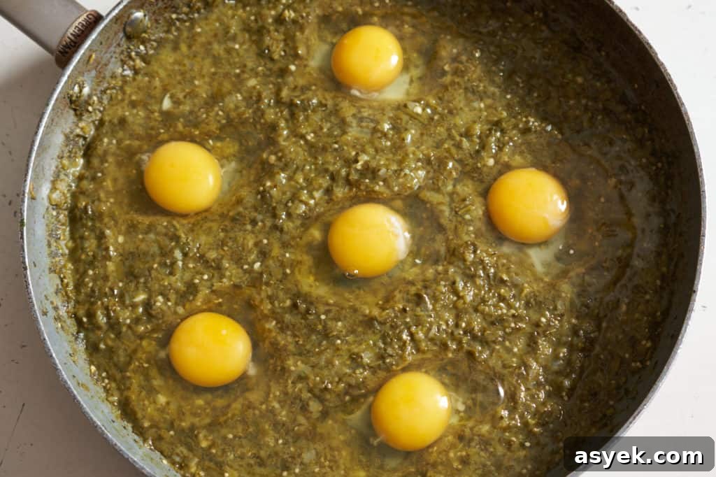 Six raw eggs nestled into the sauce in a large skillet.