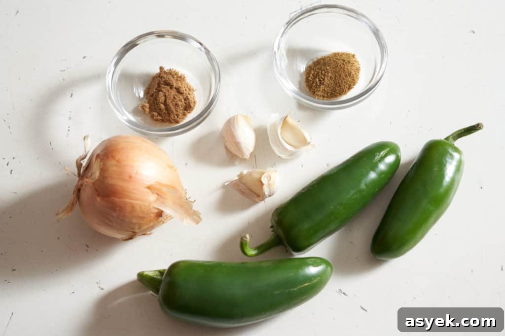 Jalapeño peppers, an onion, three garlic cloves, and two small glass bowls with spices.
