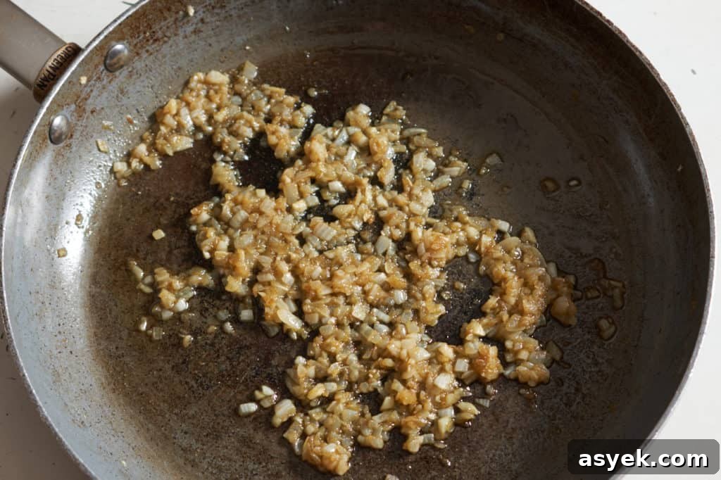 Diced onions seasoned with spices in a large skillet.
