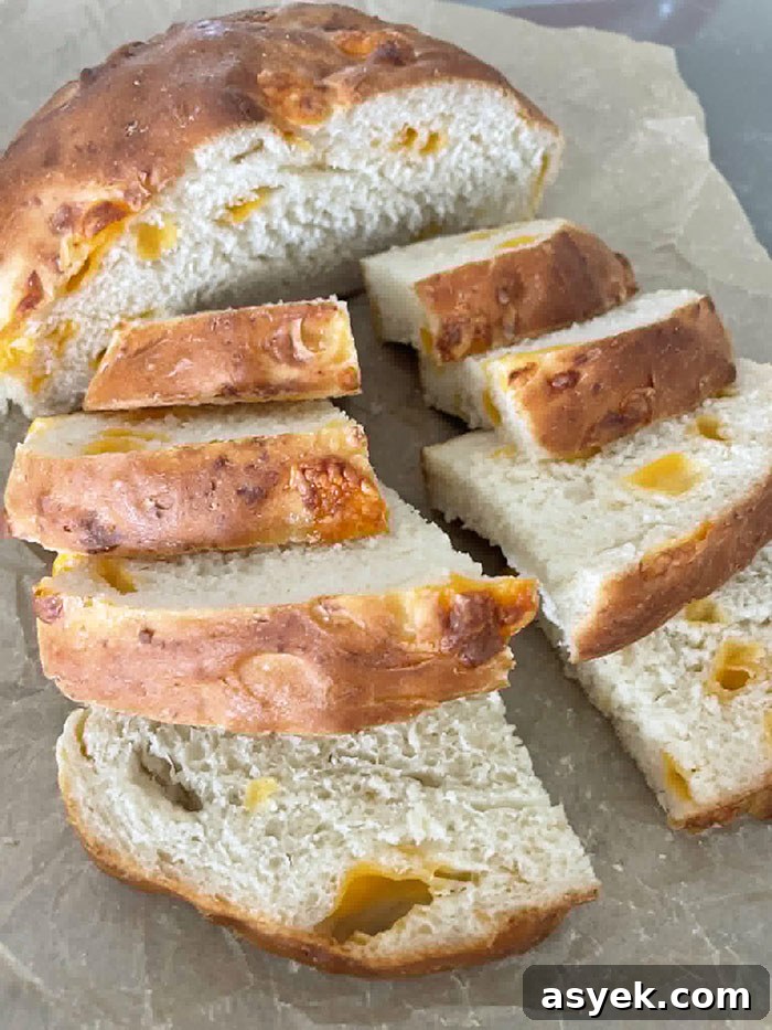 Easy Cheesy Bread sliced in half with one half sliced into 8 pieces sitting on parchment paper.
