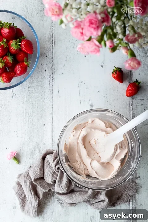A bowl of strawberry frosting with some flowers