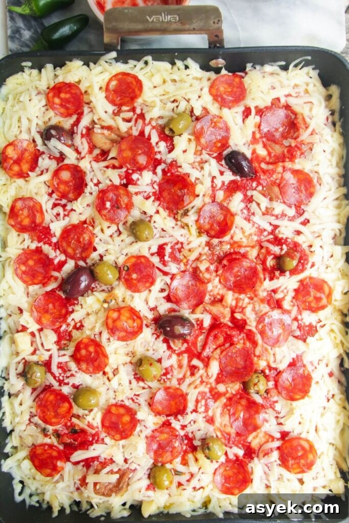 Pepperoni Focaccia Pizza Bread with Crispy Cheese Crust 11 Focaccia pizza topped with cheese, pepperoni and olives in a large oven dish.