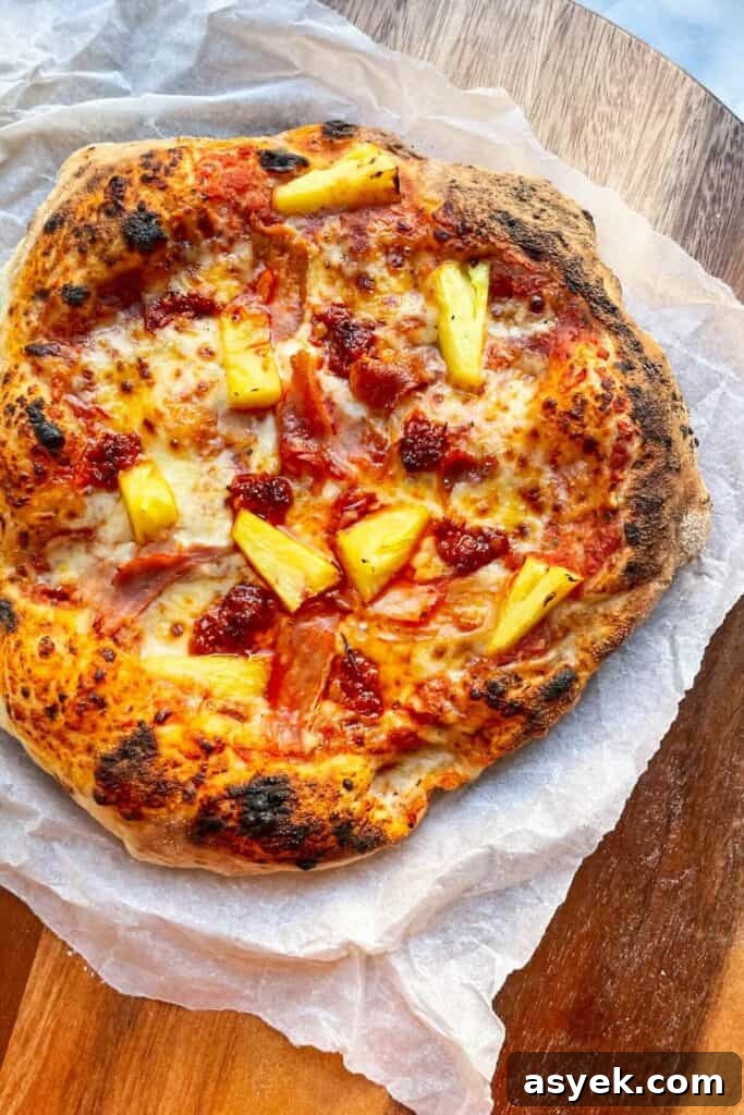 Pepperoni Focaccia Pizza Bread with Crispy Cheese Crust 17 Spicy Hawaiian pizza on baking paper on a round wooden board.