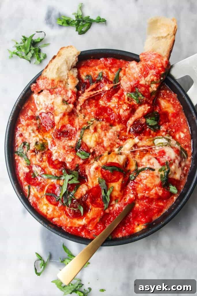 Pepperoni Focaccia Pizza Bread with Crispy Cheese Crust 20 Cheesy pepperoni topped pizza dip with two pieces of bread and a spoon inside.