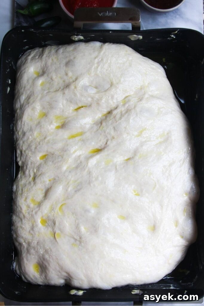 Pepperoni Focaccia Pizza Bread with Crispy Cheese Crust 7 Focaccia dough risen in an oven tray.