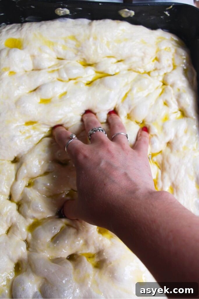 Pepperoni Focaccia Pizza Bread with Crispy Cheese Crust 8 Fingers dimpling focaccia dough in a large oven pan.