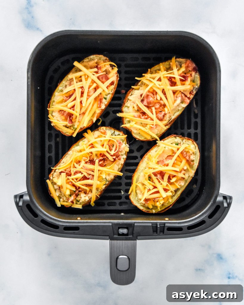 air fryer twice baked potatoes with toppings in the air fryer basket before baking again.