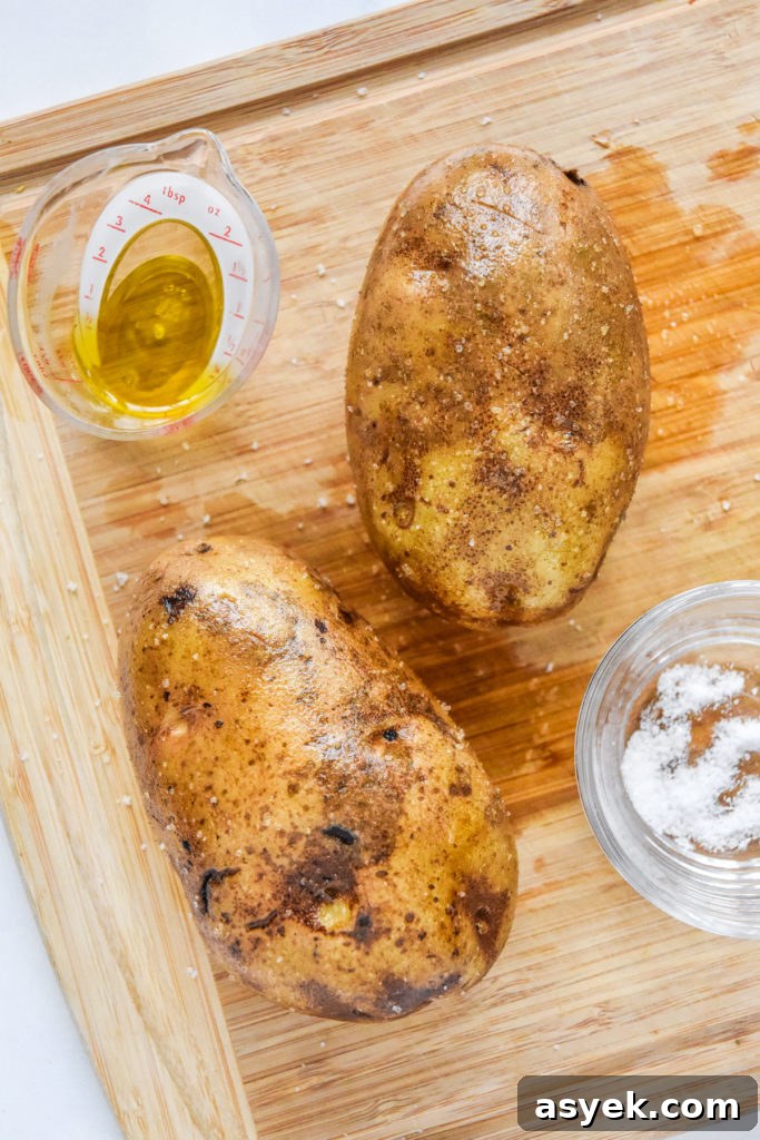 raw russet potatoes covered in oil and salt before baking.