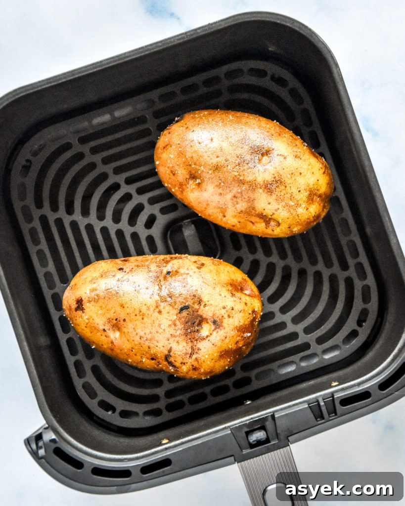 raw russet potatoes in the air fryer basket before baking.