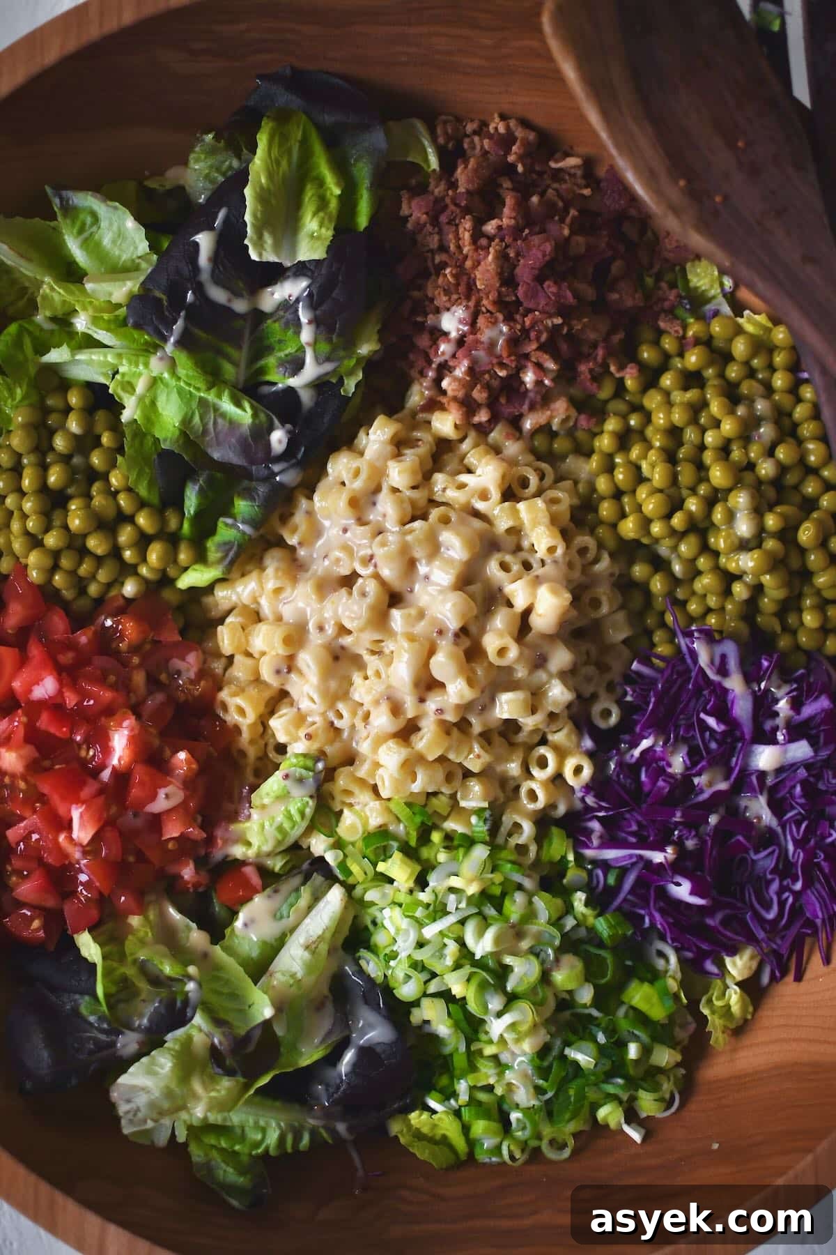 Adding all the toppings to the dressed greens before mixing it all together.