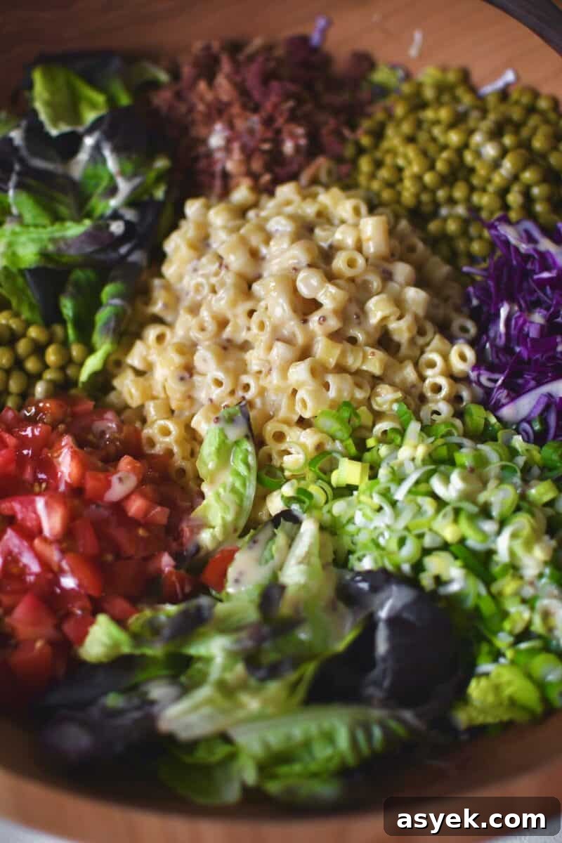 Adding all the toppings to the dressed greens before mixing it all together.