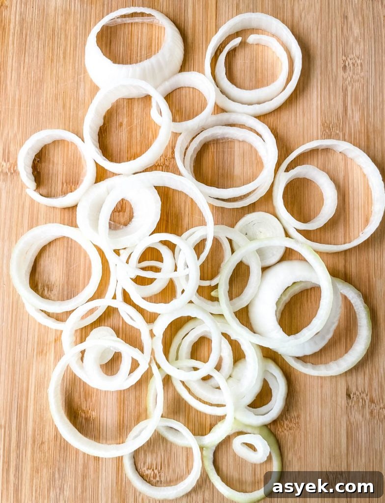 raw onions sliced into circles on a bamboo cutting board