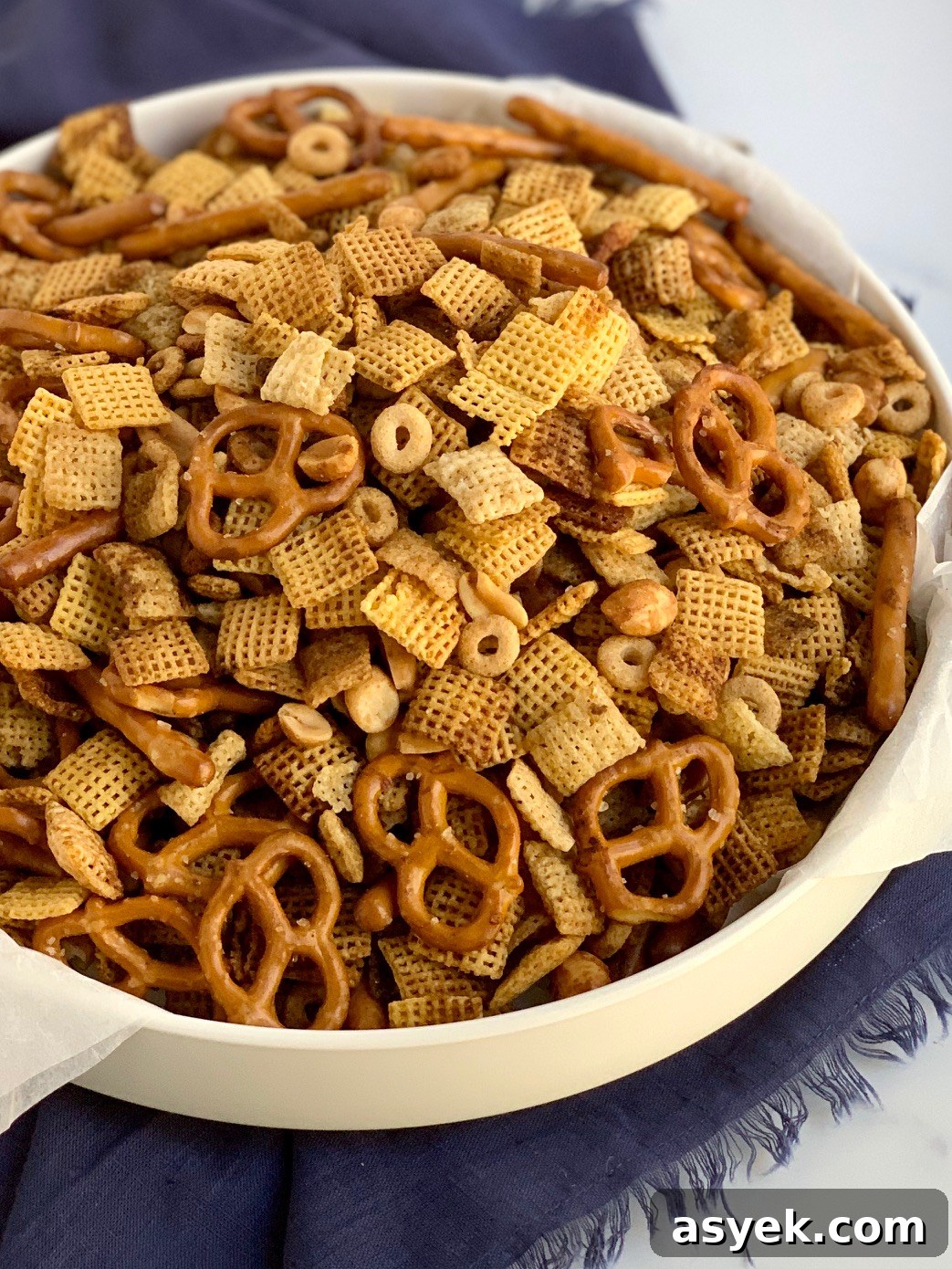 A large bowl of chex mix with peanuts, pretzels, and cereal.