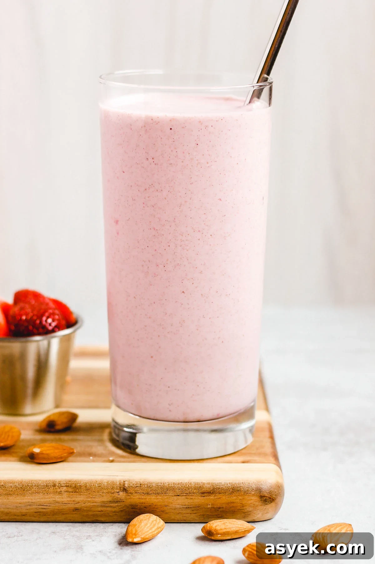 Creamy Dairy-Free Strawberry Almond Smoothie Recipe 2 side view of strawberry almond smoothie in a tall glass with stainless steel straw