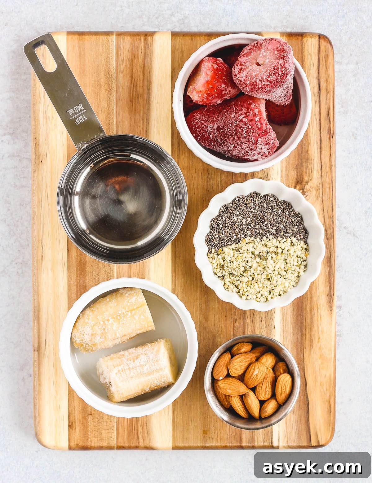 Creamy Dairy-Free Strawberry Almond Smoothie Recipe 3 strawberry almond smoothie ingredients portioned out in little bowls sitting on a wood cutting board
