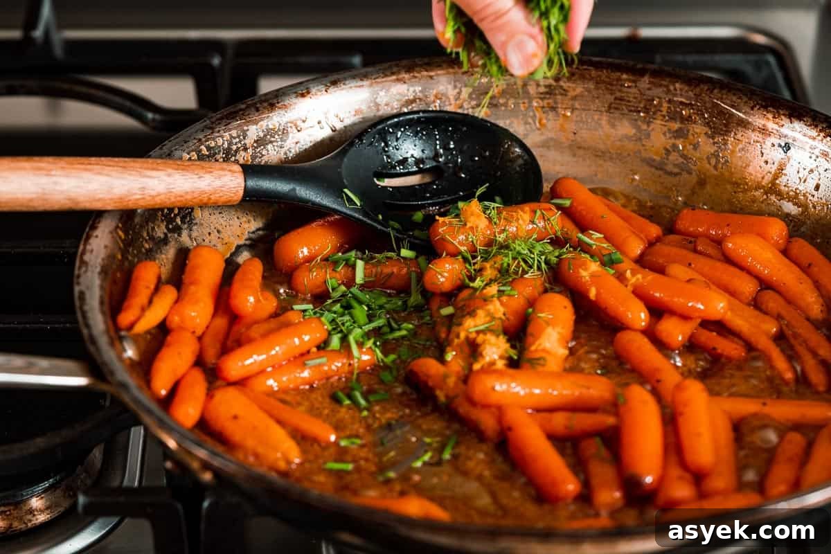 fresh herbs being sprinkled overtop pan of honey orange glazed carrots