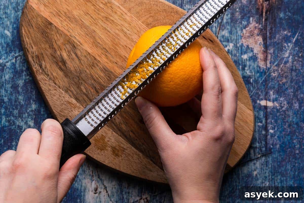 microplane zesting an orange on wooden cutting board
