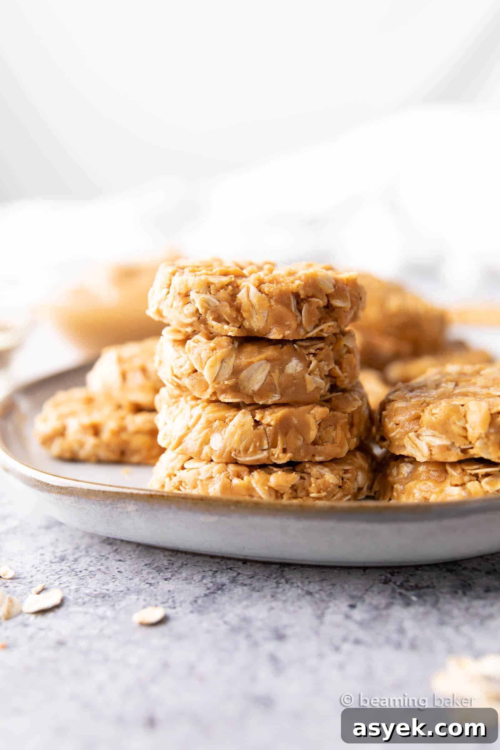 Stack of peanut butter no bake cookies on a gray plate with more cookies surrounding them.